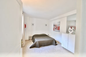 A bedroom with a bed, a nightstand, a dresser, and a painting on the wall.