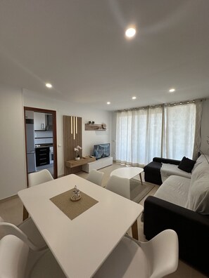 En moderne stue med spisebord, sofa og fjernsyn.