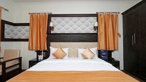 Habitación de hotel con una cama grande, dos mesitas de noche, un armario y un cabecero con diseño texturizado.