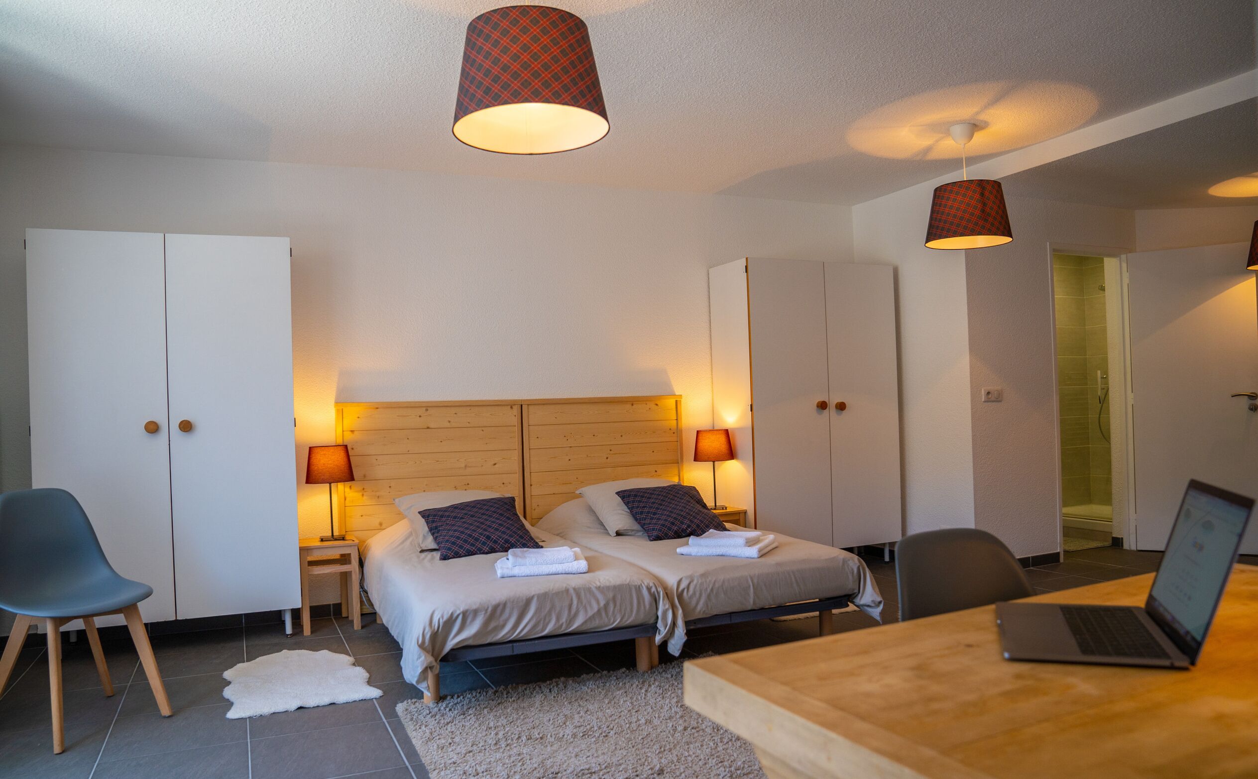 Une chambre moderne avec deux lits, un bureau et un ordinateur portable.