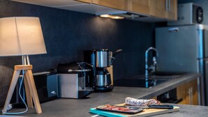 A modern kitchen with a coffee maker, a kettle, and a cutting board with a sausage.
