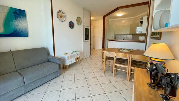 A compact living space with a sofa, a dining table, and a small kitchenette. - Bright apartment with shared pool (Porto Santa Margherita)
