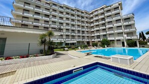 Un hôtel à plusieurs étages doté d’une piscine, d’un espace extérieur aménagé et d’un jardin paysager.