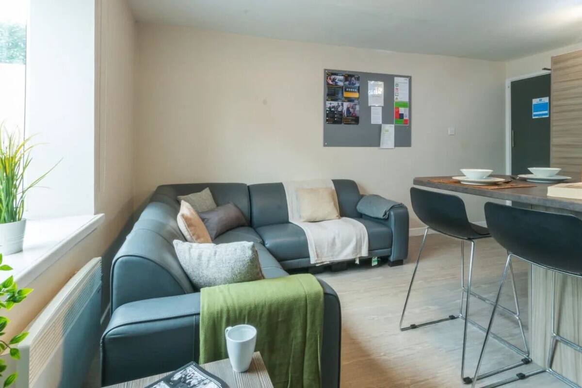 A modern living room with a sectional sofa, a dining area with bar stools, and a kitchen counter.