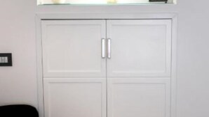 A white wardrobe with two doors and a small shelf above it.