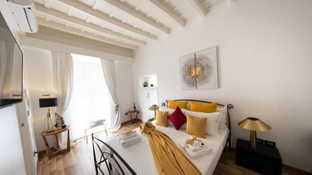 A hotel room with a bed, bedside table, lamp, and artwork on the wall.