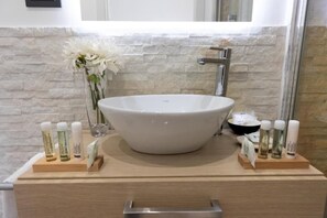Un baño con un lavamanos de pedestal grande, un espejo y artículos de tocador sobre bandejas de madera.
