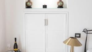 A white wardrobe with two doors, a glass bottle, and a lamp on a table.