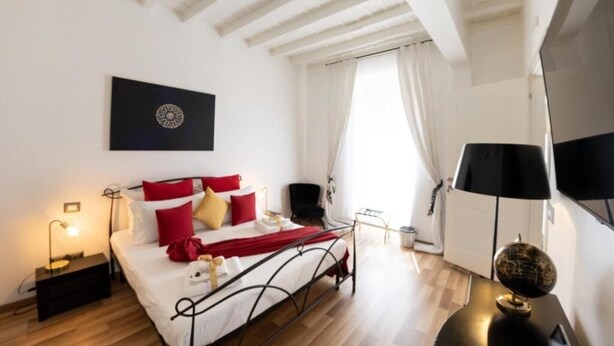 A modern bedroom with a bed, bedside tables, a lamp, and a globe on a side table. - Barcaccia Luxury Suites: Executive Suite 2 (Roma)