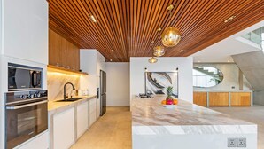 Una cocina moderna con techo de madera, electrodomésticos de acero inoxidable y encimera de mármol.
