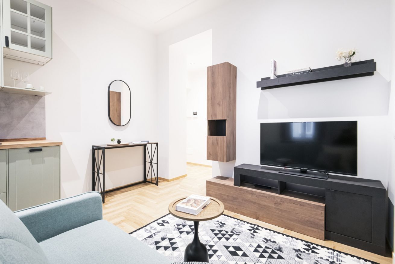 Ein modernes Wohnzimmer mit einer Couch, einem Couchtisch, einem Fernseher und einem Bücherregal.