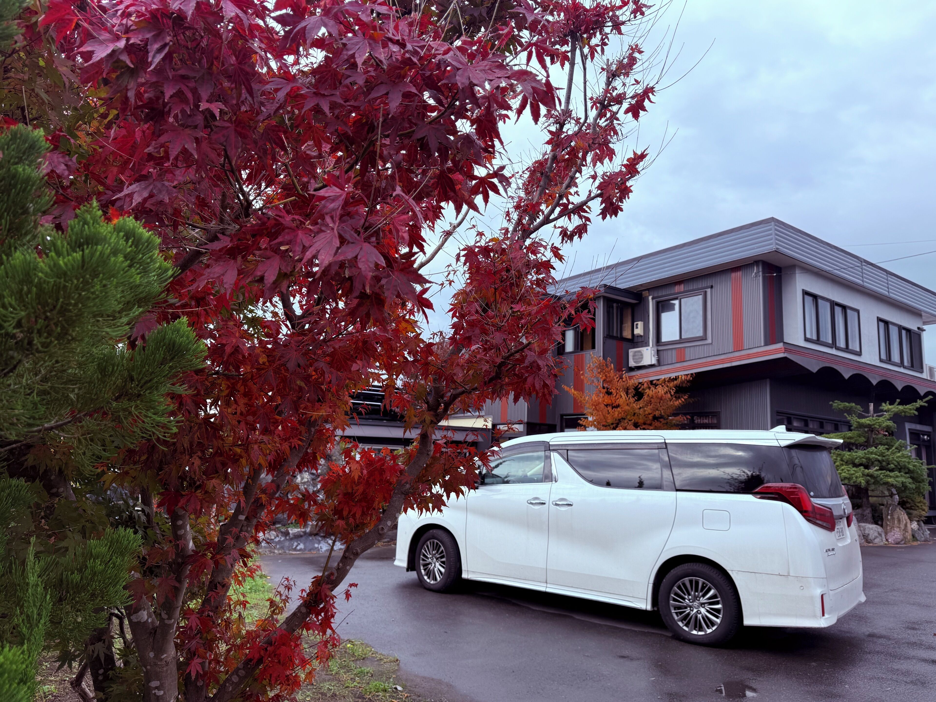 Un SUV blanco estacionado frente a una casa moderna de dos plantas con garaje.