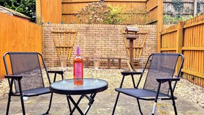 An outdoor seating area with two chairs and a table, a bottle of wine, and a wooden fence in the background. - Quiet 2bedroom Home-garden-parking-family Friendly (Swansea)
