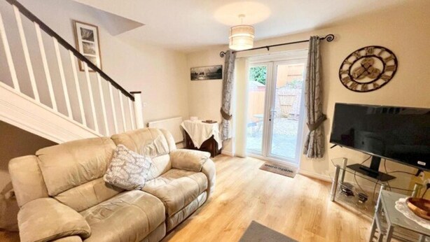A living room with a beige sofa, a flat-screen TV, and a staircase. - Quiet 2bedroom Home-garden-parking-family Friendly (Swansea)