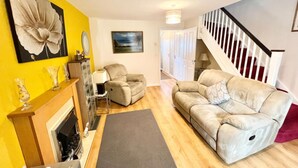 A living room with a fireplace, a sofa, a coffee table, and a rug. - Quiet 2bedroom Home-garden-parking-family Friendly (Swansea)