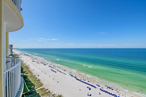 A beach with rows of umbrellas and a clear view of the ocean.