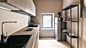 Een kleine keuken met een zwarte spoelbak, roestvrijstalen apparatuur en een houten plafond.