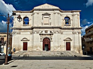 A historic building with a symmetrical facade, large wooden doors, and a central archway. - Nido di Noto (Noto)