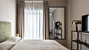 Een hotelkamer met een groot bed, een nachtkastje met een lamp, een televisie en een spiegel aan de muur.