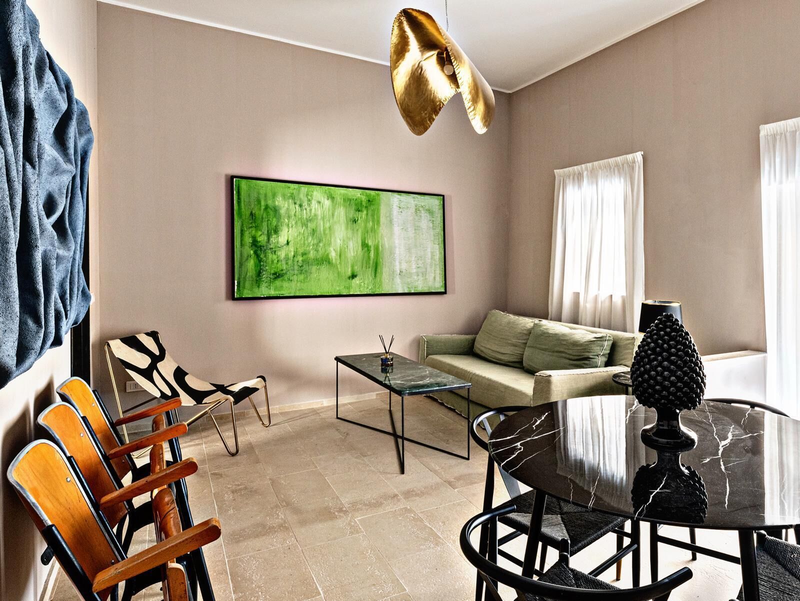 Una sala de estar moderna con un cuadro abstracto verde, un sofá, una mesa de centro y un comedor con sillas y una mesa.