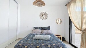 A bedroom with a bed, a window with sheer curtains, and wall decor.