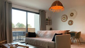 A modern living room with a sofa, coffee table, and a dining area with chairs.