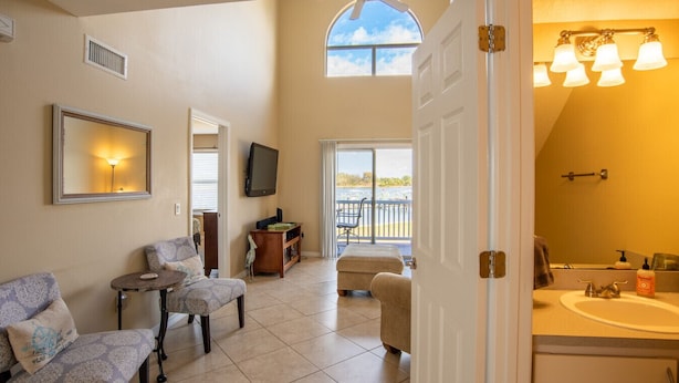 A spacious living area with a balcony, a television, and a comfortable seating arrangement.