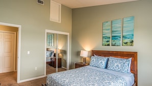 A bedroom with a bed, nightstands, a mirror, and artwork on the wall.