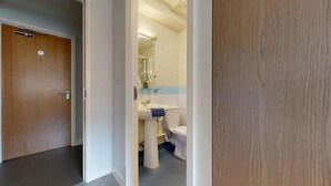 A bathroom with a sink, toilet, and mirror. - Student Only Kopa (Preston)