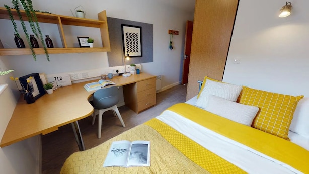 A compact bedroom with a bed, desk, chair, and shelving unit. - Student Only Kopa (Preston)