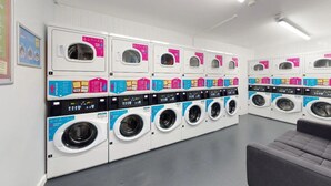 A row of front-loading washing machines in a commercial laundry facility. - Student Only Kopa (Preston)