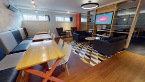 A modern lounge area with seating, tables, and a television screen displaying the word "heart". - Student Only Kopa (Preston)