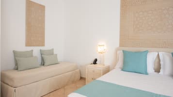 A bedroom with a bed, a bedside table, a lamp, and a wall-mounted artwork.