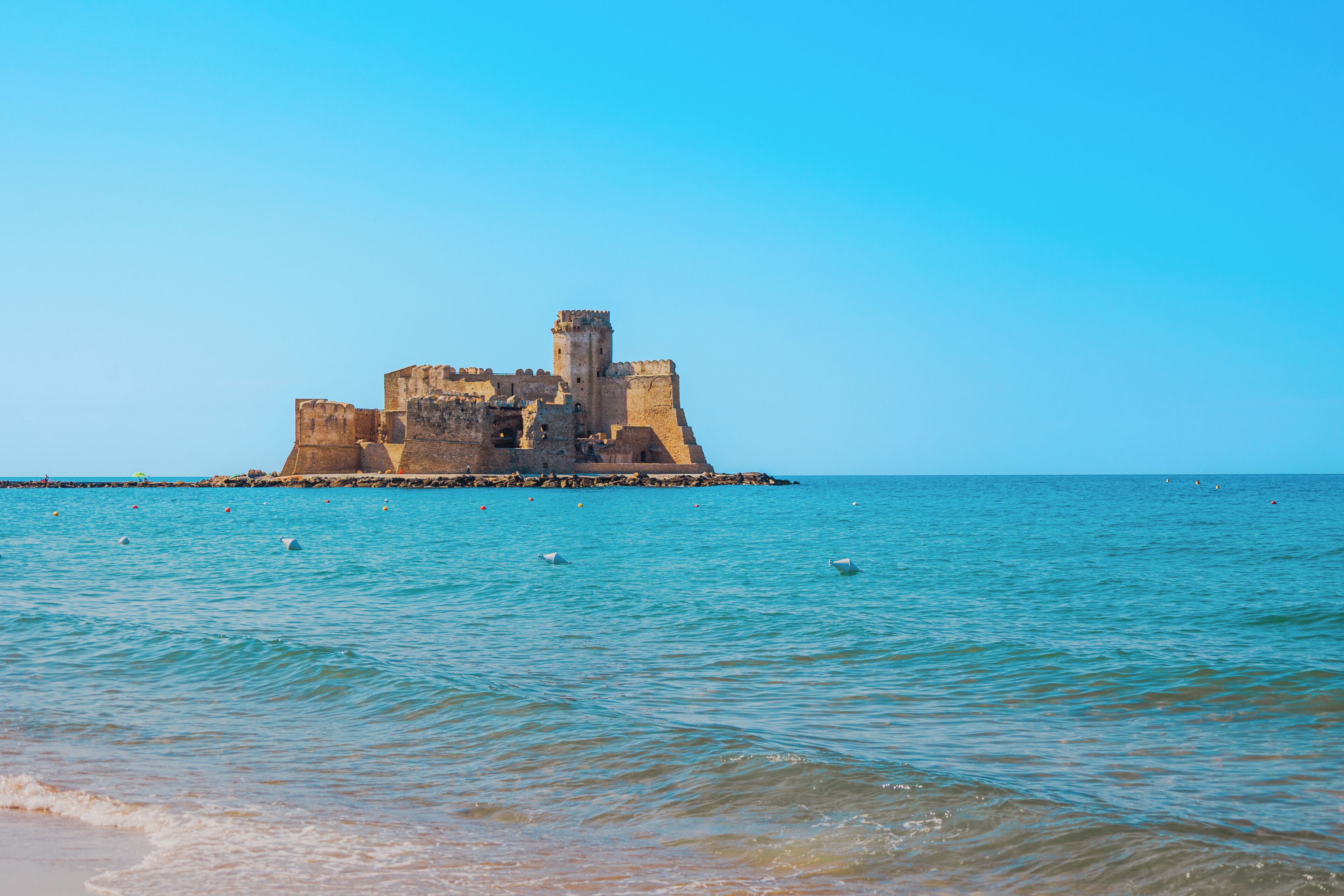 A historic castle on a small island surrounded by calm sea.