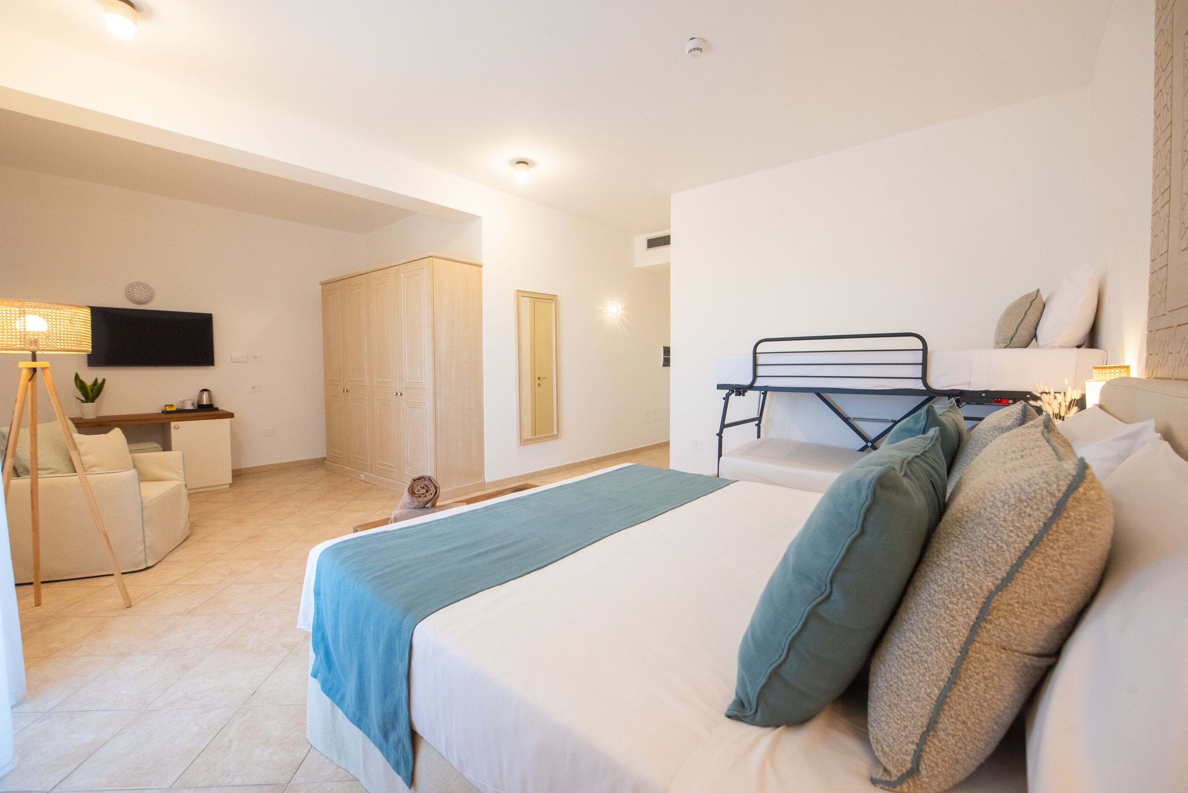 Ein Schlafzimmer mit Bett, Schreibtisch, Stuhl, Fernseher und Kleiderschrank.