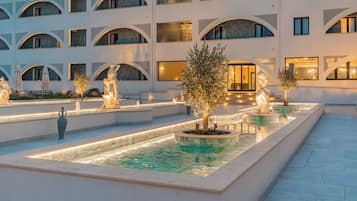 Un patio con una fuente, estatuas y un edificio con varios balcones.