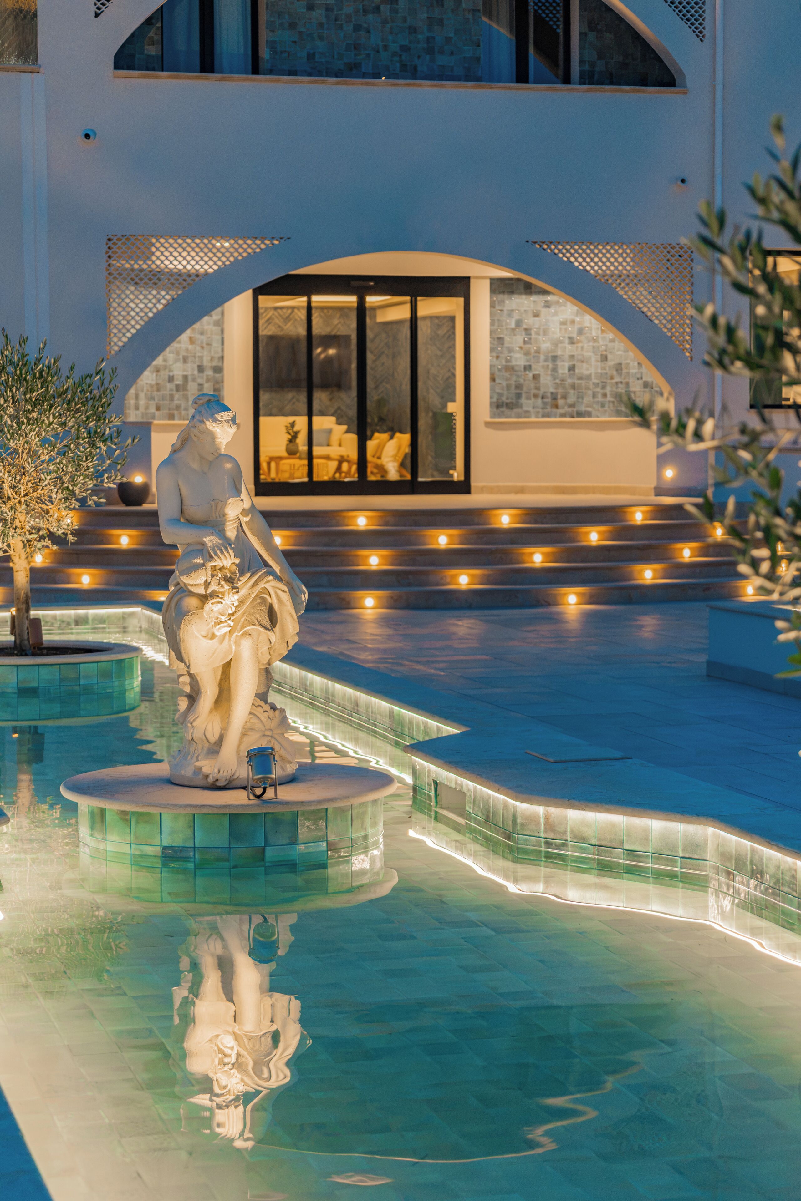 Eine Statue in einem Pool vor einem modernen Gebäude im Hintergrund.