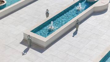 A rectangular water feature with multiple fountains, surrounded by a tiled walkway.