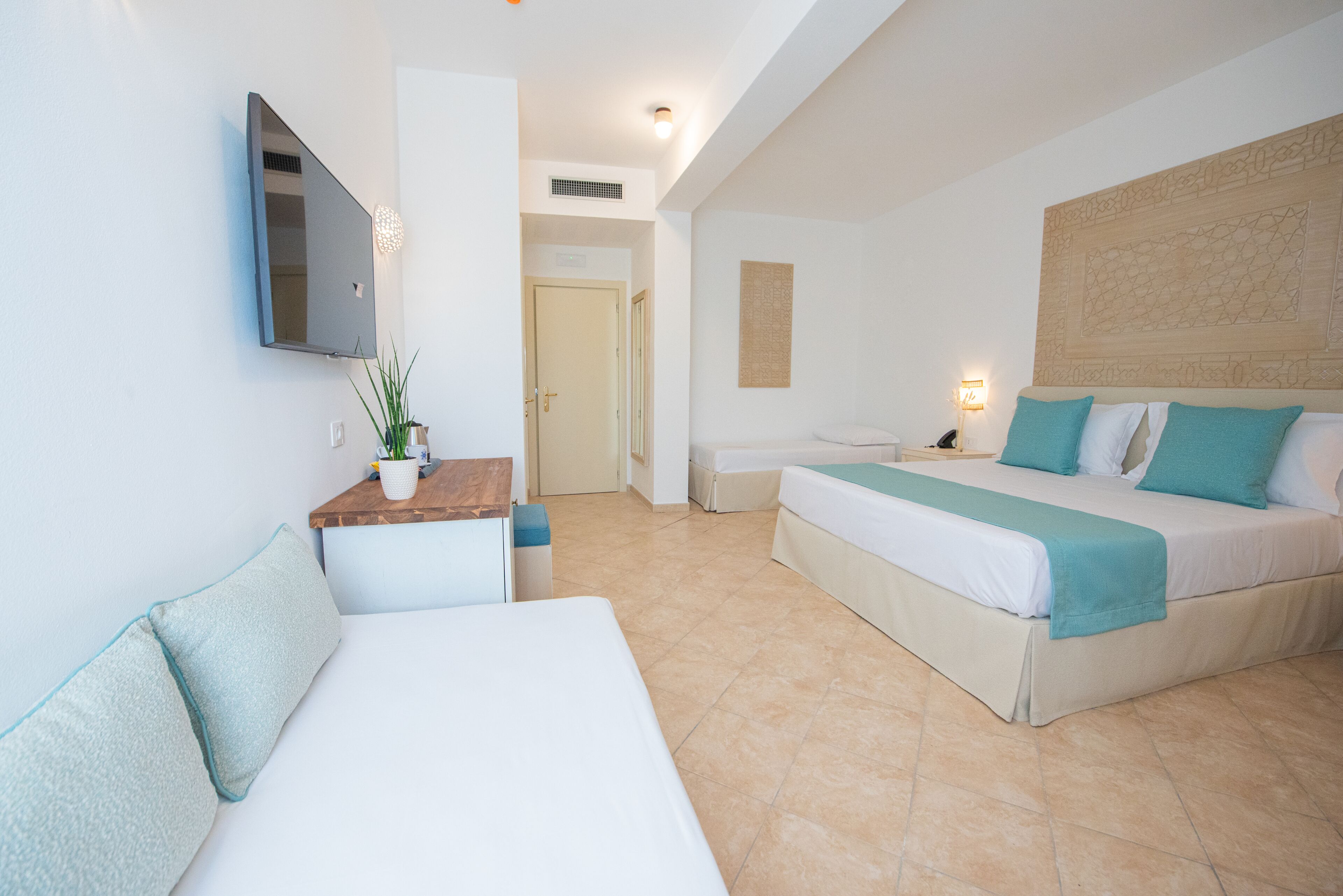 Una habitación de hotel con cama, sofá, escritorio y televisor.
