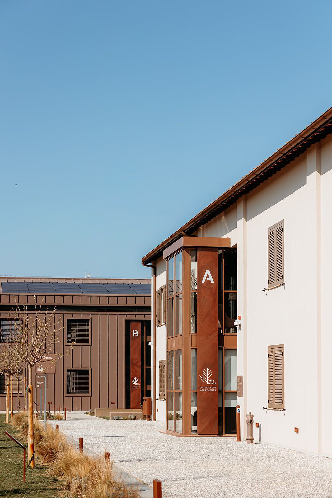 A modern building with a clear entrance, marked with letters A and B, and a sign indicating 'Villa Madère San Rossore Apartments.'
