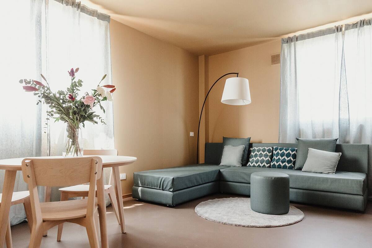 Ein modernes Wohnzimmer mit einer Eckcouch, einem runden Tisch und einem Blumenstrauß.