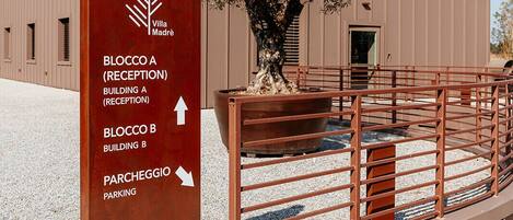 Ein Gebäude mit einer Rezeption, auf der 'BLOCCO A (RECEPTION)' steht, und einem Parkplatz, auf dem 'PARCHEGGIO' steht.