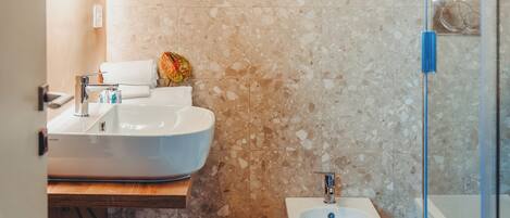 A bathroom with a sink, bidet, and glass shower enclosure.