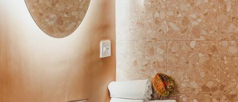 A bathroom with a large oval mirror, a white sink, and a wooden countertop.