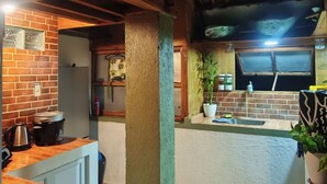A kitchen with wooden beams, a brick wall, and a wooden countertop.