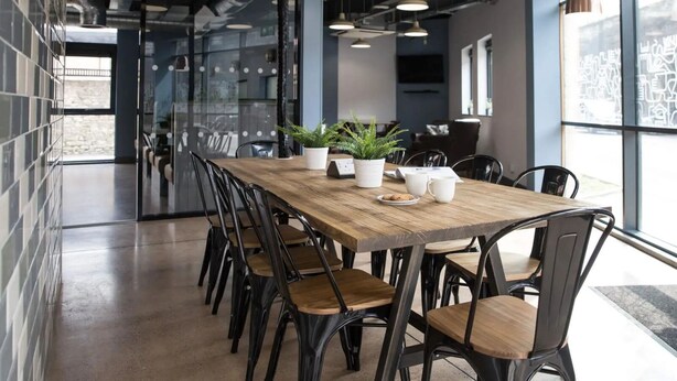 Une salle de réunion moderne, dotée d’une longue table en bois, de chaises noires, de plantes en pot et d’un mur en verre offrant une vue sur la ville.
