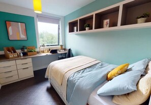 A bedroom with a bed, desk, and shelving unit.