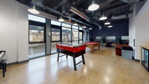 Un espace de loisirs intérieur comprenant une table de baby-foot, une table de billard et des sièges.