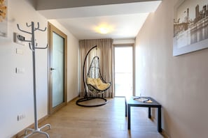 A hallway with a hanging chair, a table, and a coat rack.