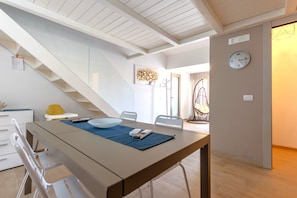 A modern dining area with a table, chairs, and a staircase.